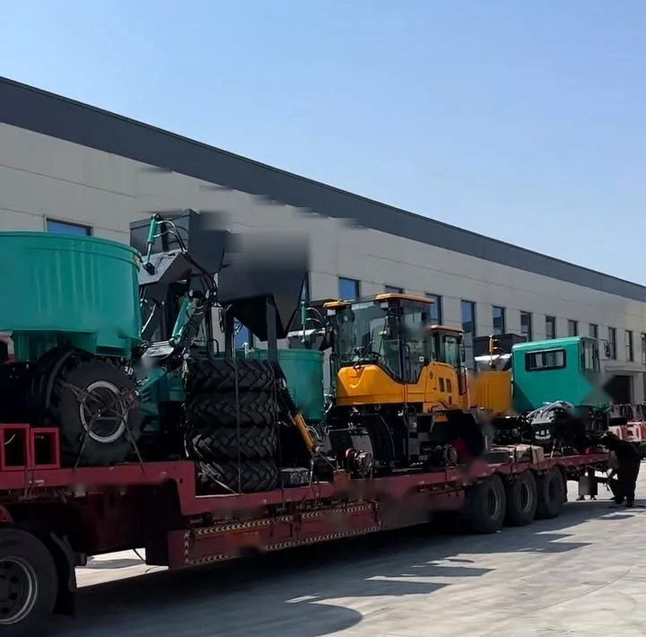 Two self-loading concrete mixers riding on an open low-bed trailer, leaving a plant yard